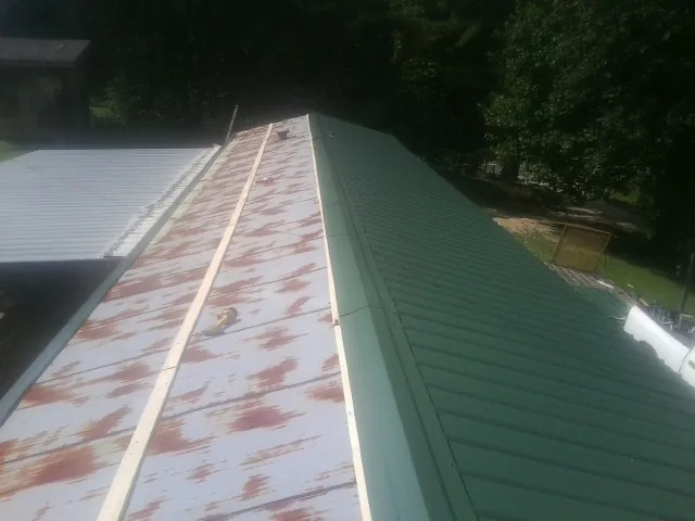 Old rusted panels beside newly installed green metal roofing — Wind Damage Roof Repair by Roofing Brothers in New Derry