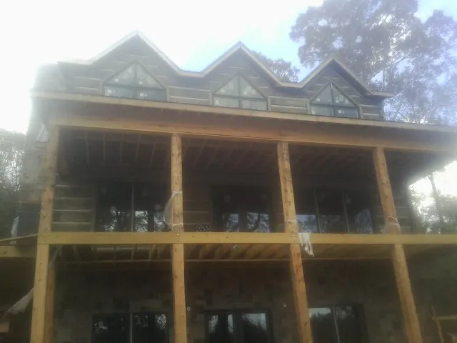 Dormers and porch framing on a large log home under construction — Roof Coating work by our crew in New Derry