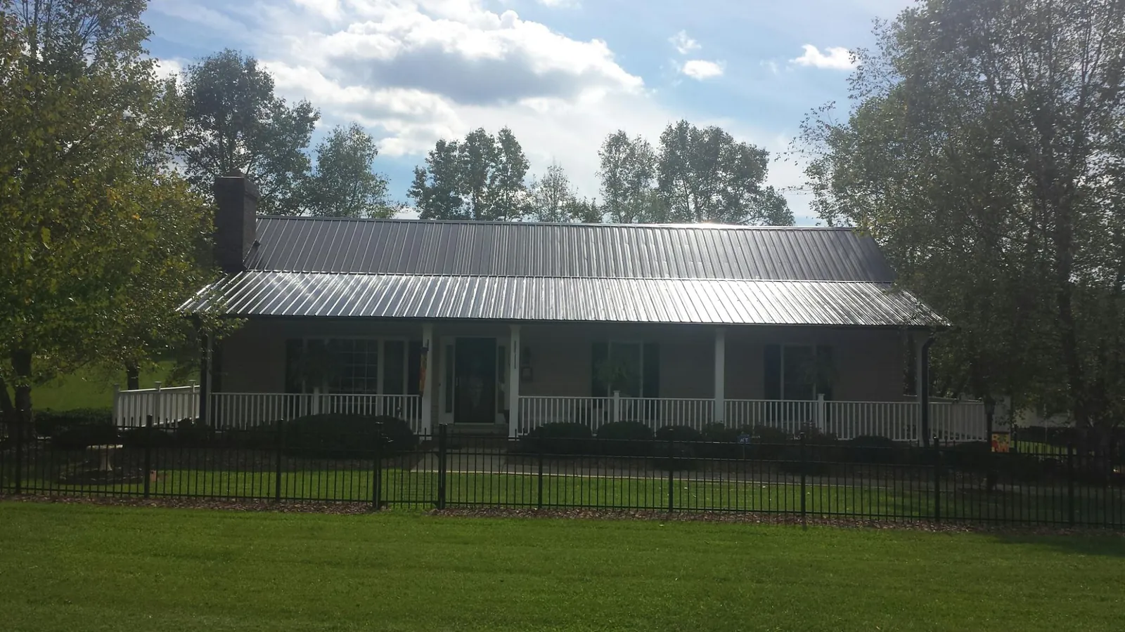 Gray metal roof on a brick ranch with a full width front porch — Gutter Guard Installation work by our crew in New Derry