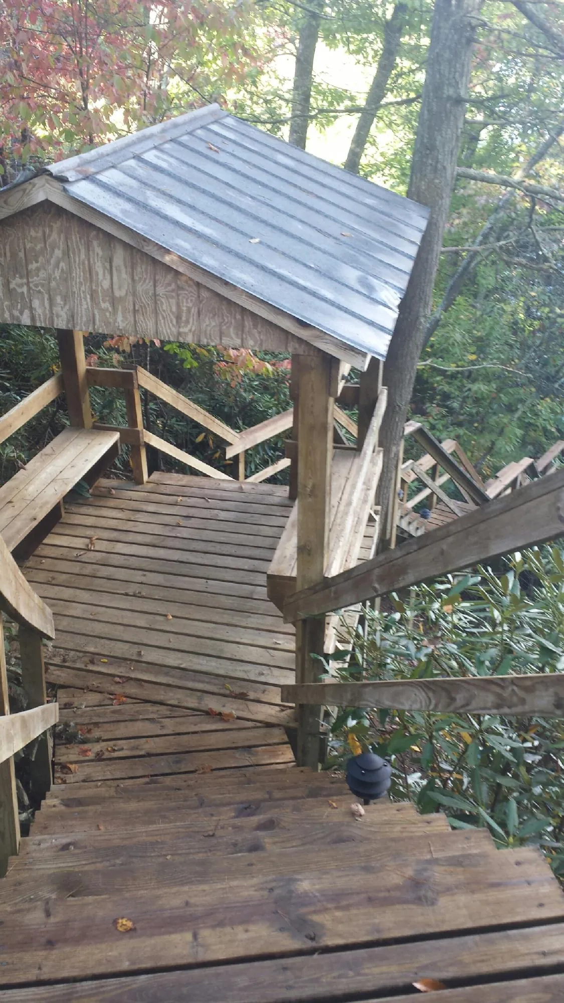 Metal roofed shelter over wooden steps on a wooded walkway — Skylight Repair & Installation work by our crew in New Derry