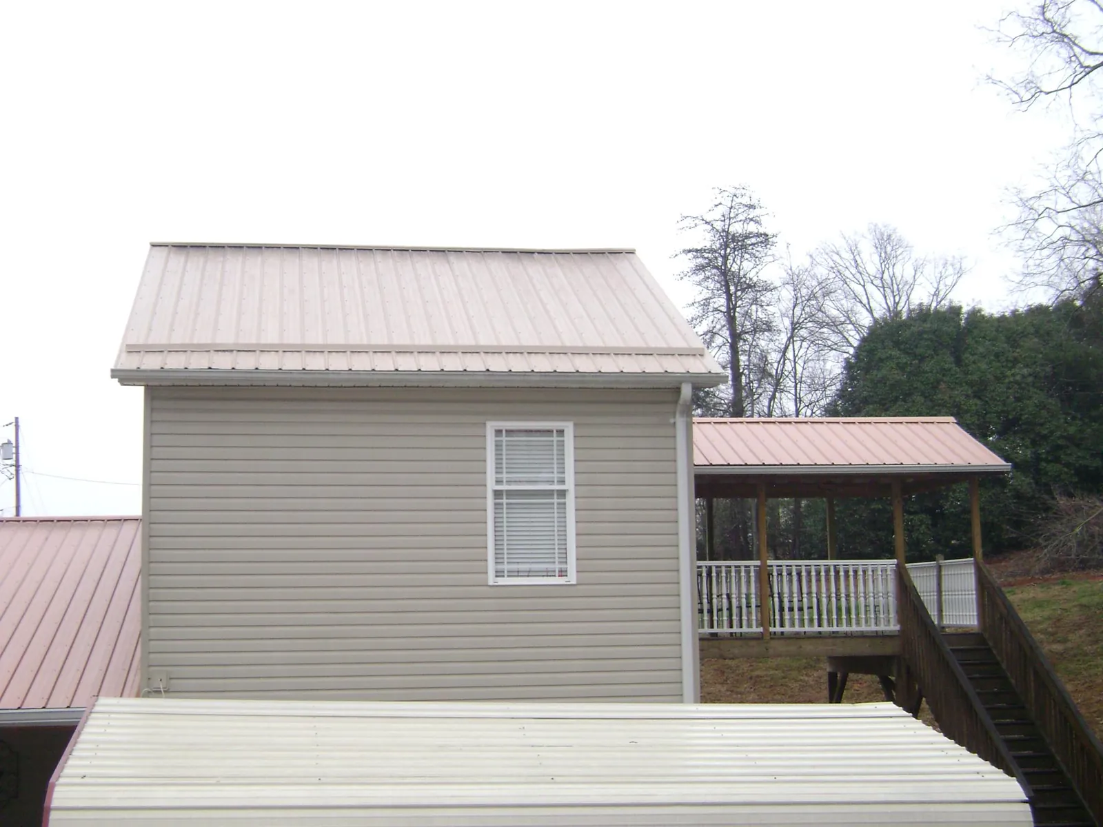 Tan metal roofs on a two story addition and attached porch, from a Roof Replacement job in New Derry