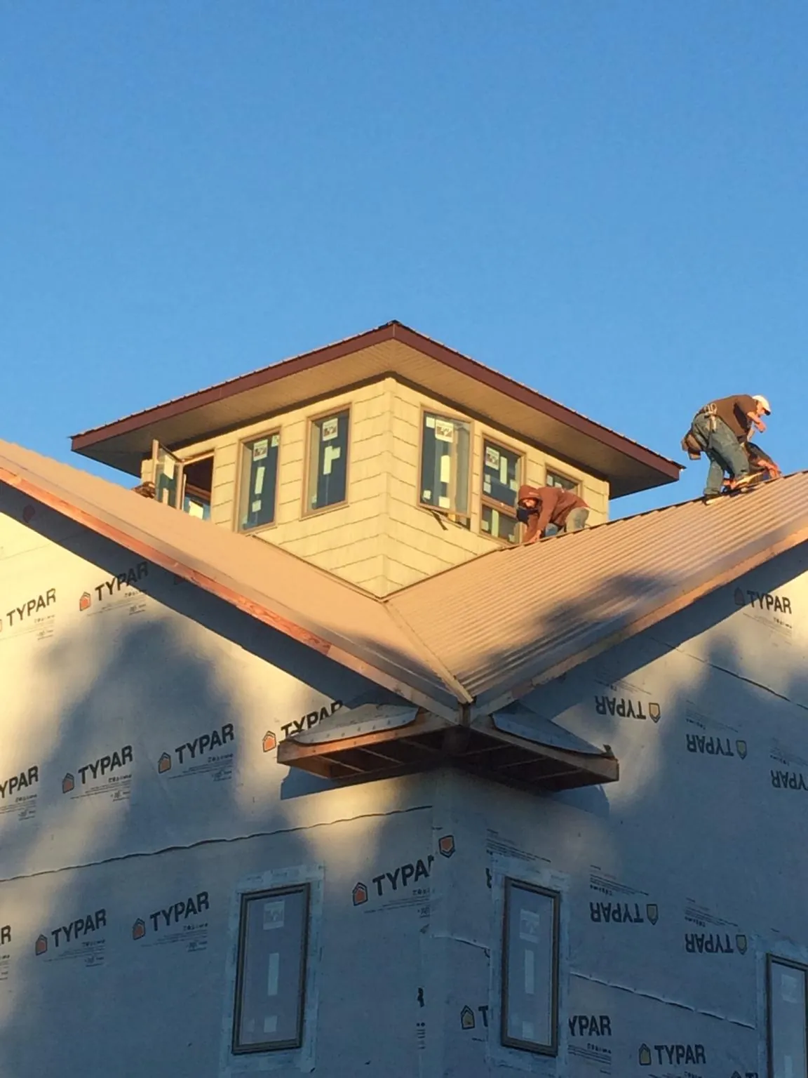 Roofers working around a rooftop cupola on a new metal roof at sunset — Roof Waterproofing in New Derry by Roofing Brothers